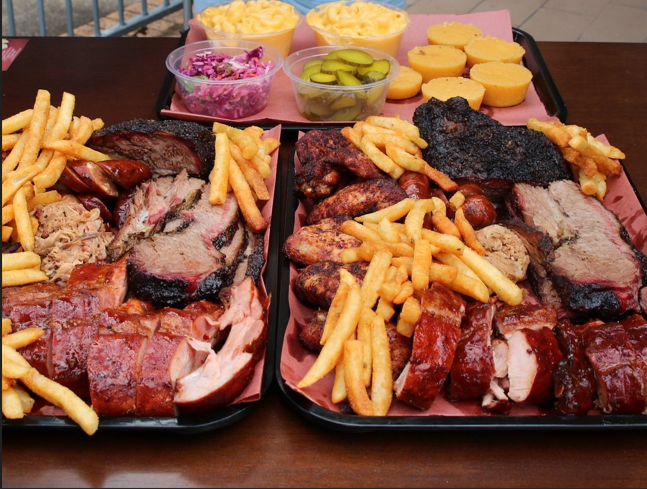 Two Southwest Barbecue trays loaded with smoked meats, fries and sides