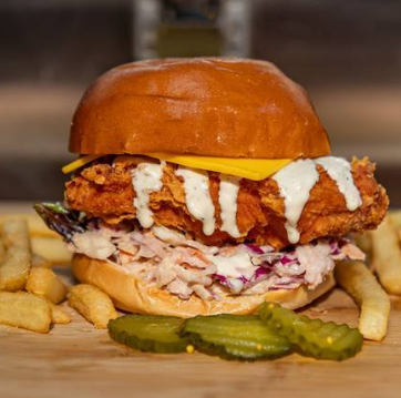 Crispy chicken burger with slaw, sauce, fries and pickles